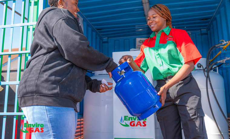 EnviroGas attendant handing a freshly filled cylinder to a smiling customer